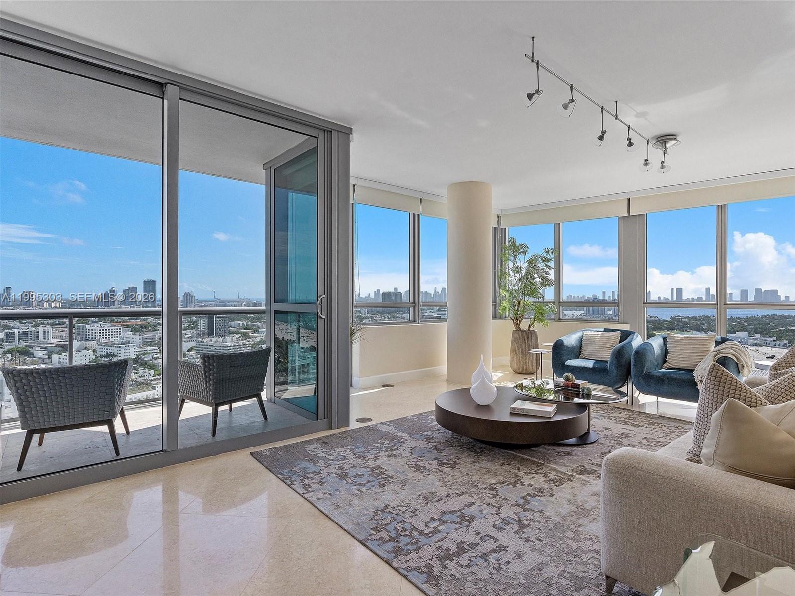 A modern living room features floor-to-ceiling windows, a balcony, and panoramic city and water views — 101 20th St # 3002, Miami Beach FL 33139, MIAMI BEACH, FL