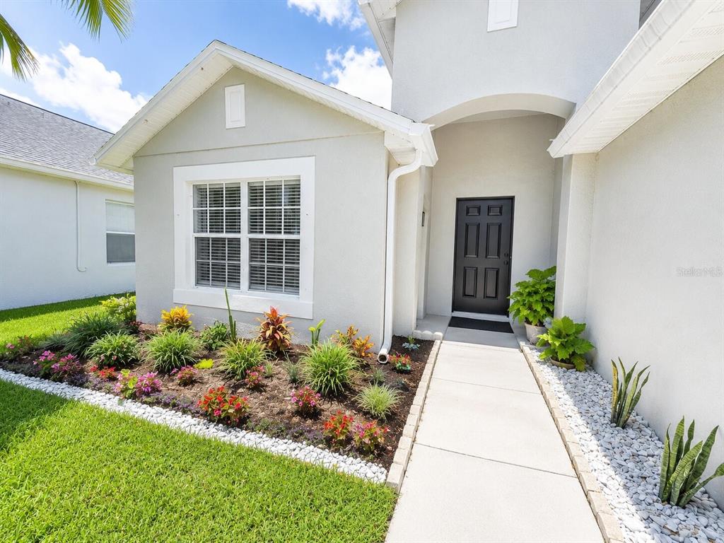 A light-colored house exterior features a front walkway, a black door, and a landscaped garden — 1926 DARLIN CIRCLE, ORLANDO, FL