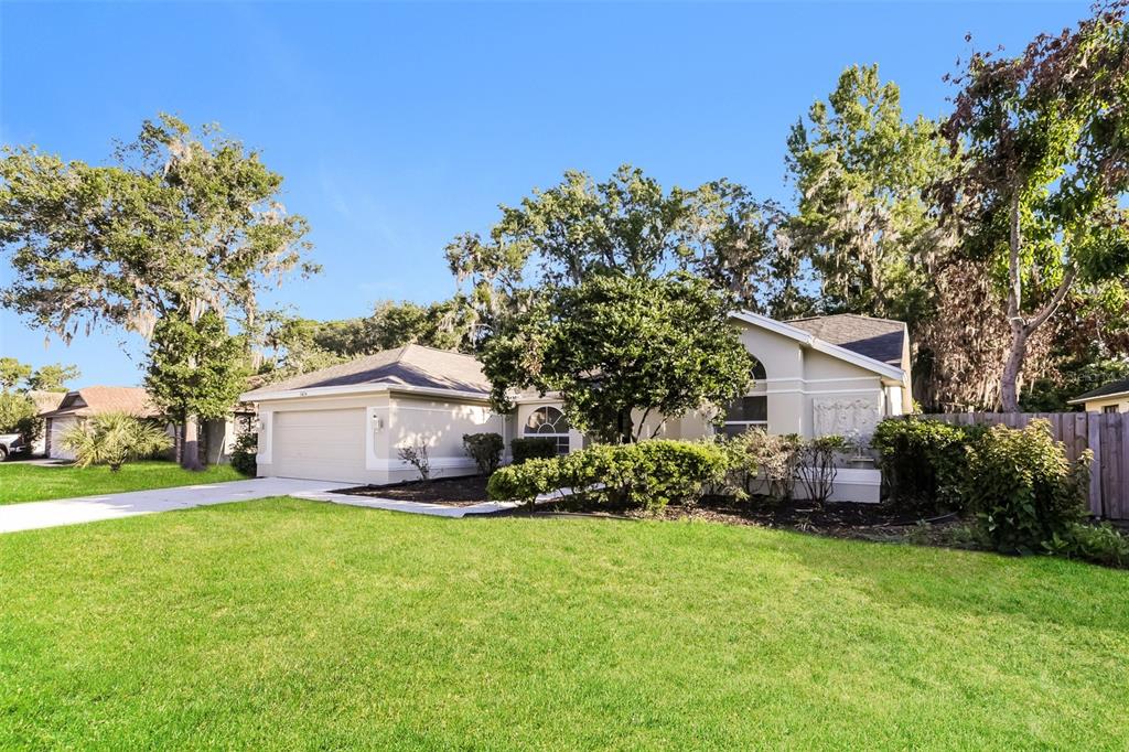 A single-story house with a beige exterior, a two-car garage, and a large front lawn — 2624 BRIDLE DRIVE, PLANT CITY, FL