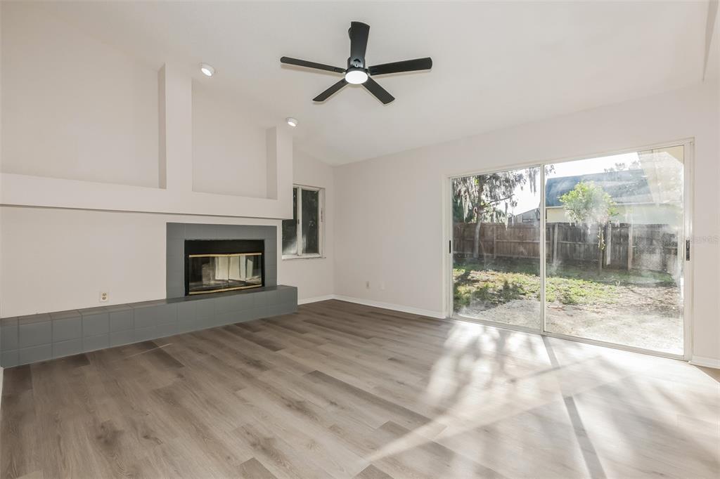 A living room features light wood-look flooring, a gray tiled fireplace, and sliding glass doors — 2624 BRIDLE DRIVE, PLANT CITY, FL