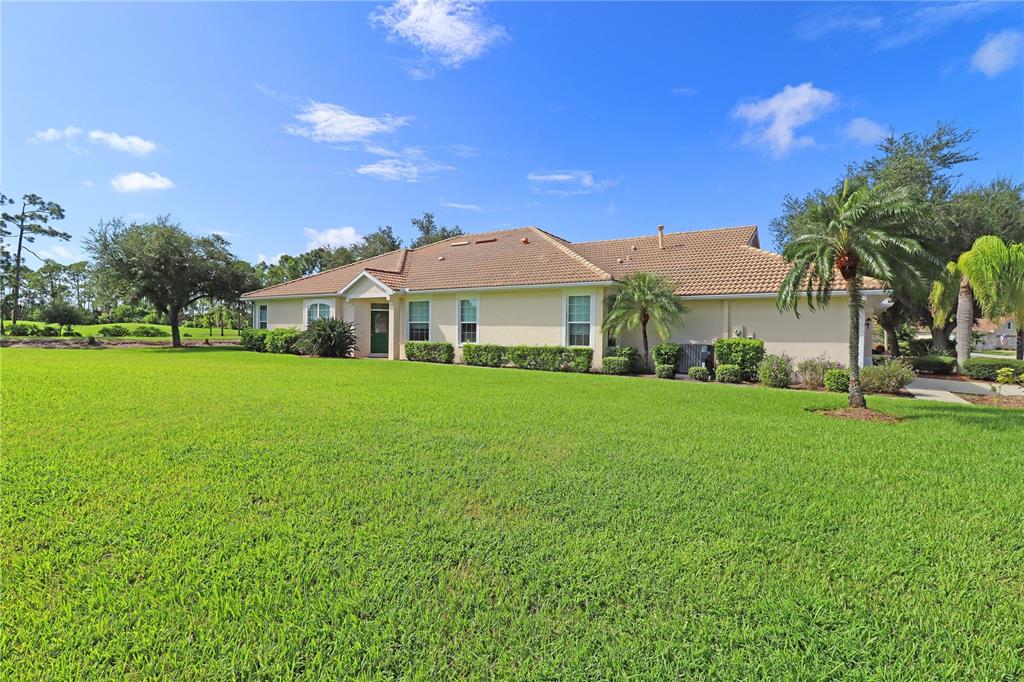 A single-story house with a tan exterior and a tiled roof sits on a lawn — 5107 WHISPERING OAKS DRIVE, NORTH PORT, FL