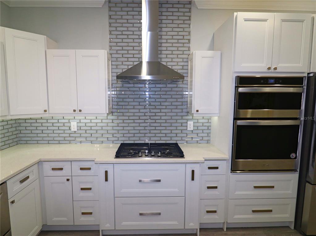 A kitchen with white cabinets, stainless steel appliances, and a gray subway tile backsplash — 5107 WHISPERING OAKS DRIVE, NORTH PORT, FL