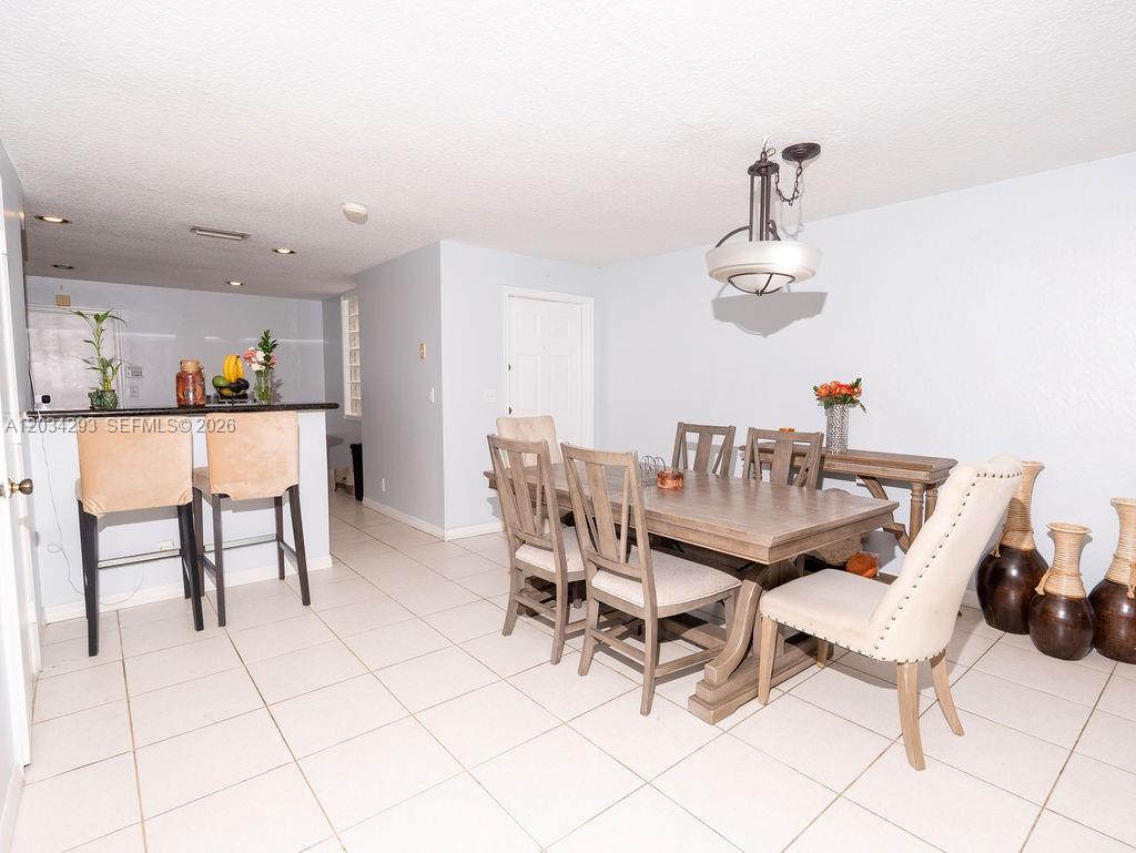 A dining area with a wooden table and chairs sits adjacent to a kitchen counter — 1611 Veracruz Ln # 17, Weston FL 33327, WESTON, FL