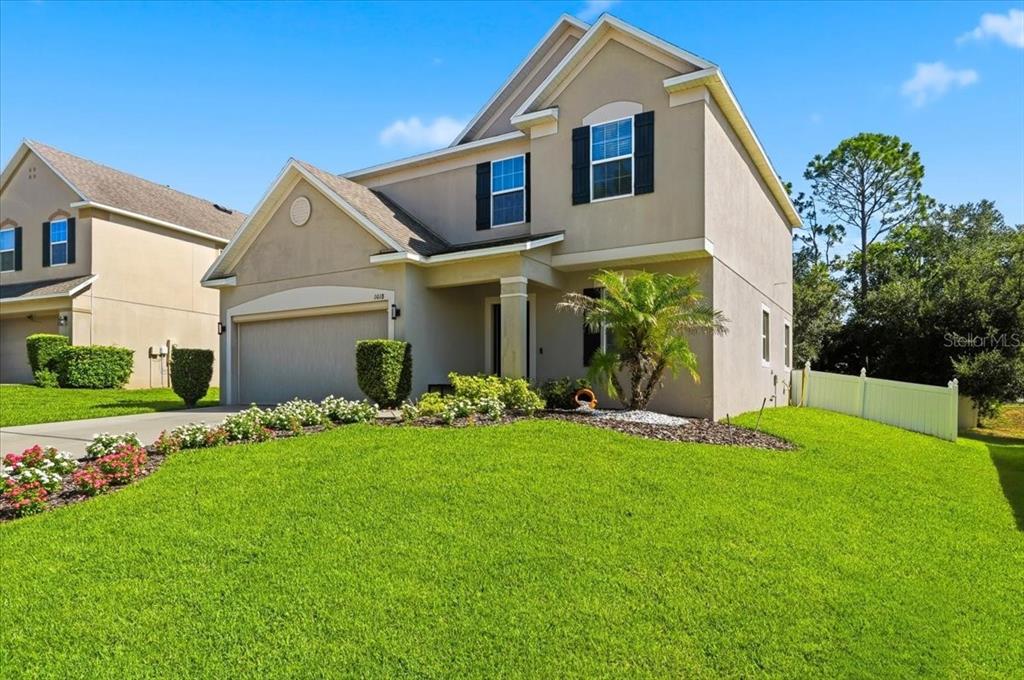 A two-story suburban house with a tan stucco exterior, a two-car garage, and green lawn — 1018 ROBERTA ROAD, LAKE WALES, FL