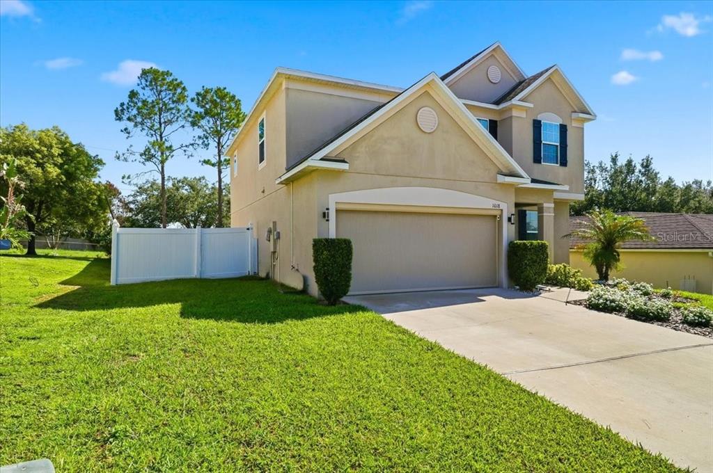 A two-story suburban house with a beige stucco exterior and a two-car garage — 1018 ROBERTA ROAD, LAKE WALES, FL