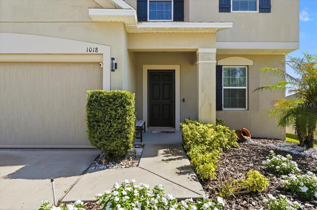 The exterior of a two-story house features a garage, a front door, and landscaping — 1018 ROBERTA ROAD, LAKE WALES, FL