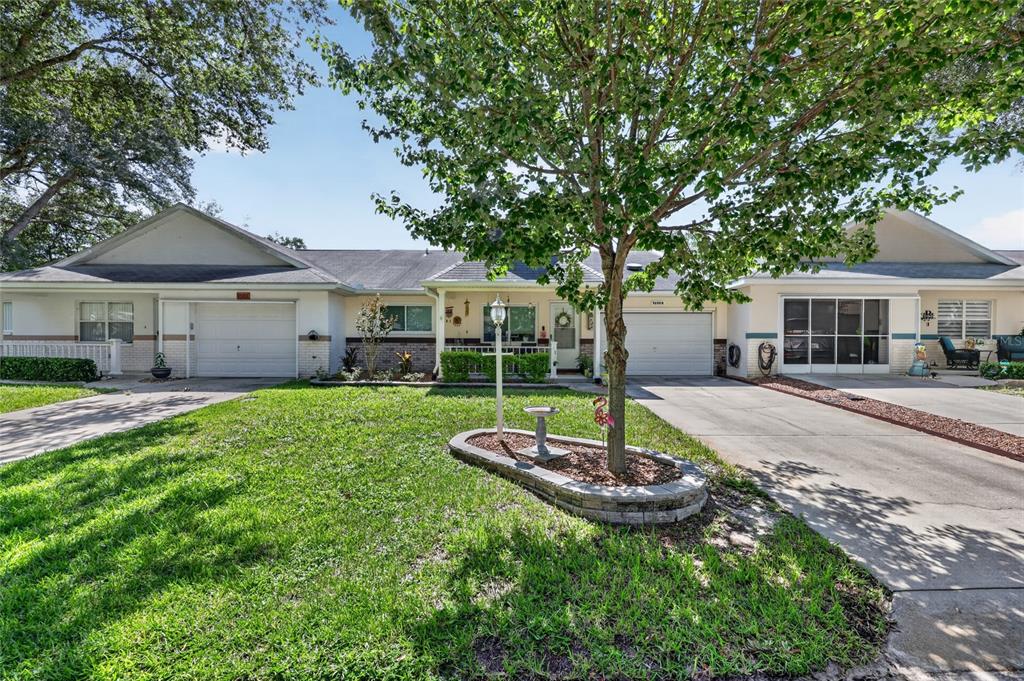 A row of single-story attached houses with garages and a front lawn under a tree — 9690 SW 95TH TERRACE UNIT B, OCALA, FL