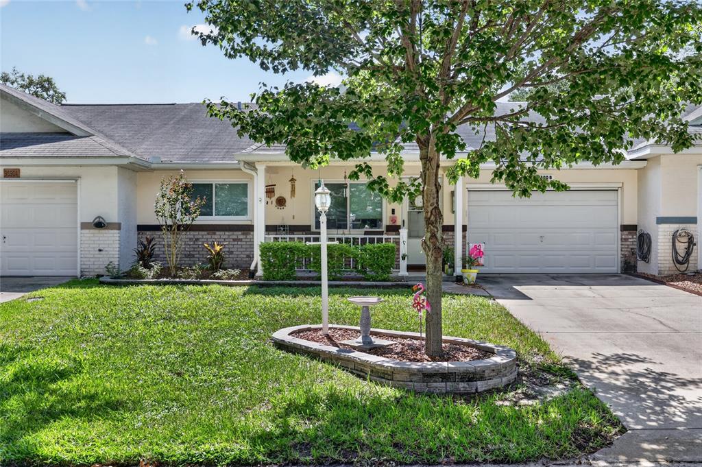 The exterior of a single-story house features a screened-in porch and a landscaped garden bed — 9690 SW 95TH TERRACE UNIT B, OCALA, FL