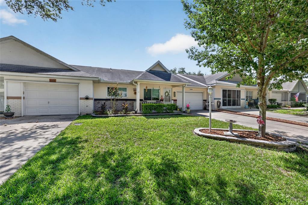 The rear exterior of a single-story house features a screened-in patio and landscaped garden beds — 9690 SW 95TH TERRACE UNIT B, OCALA, FL