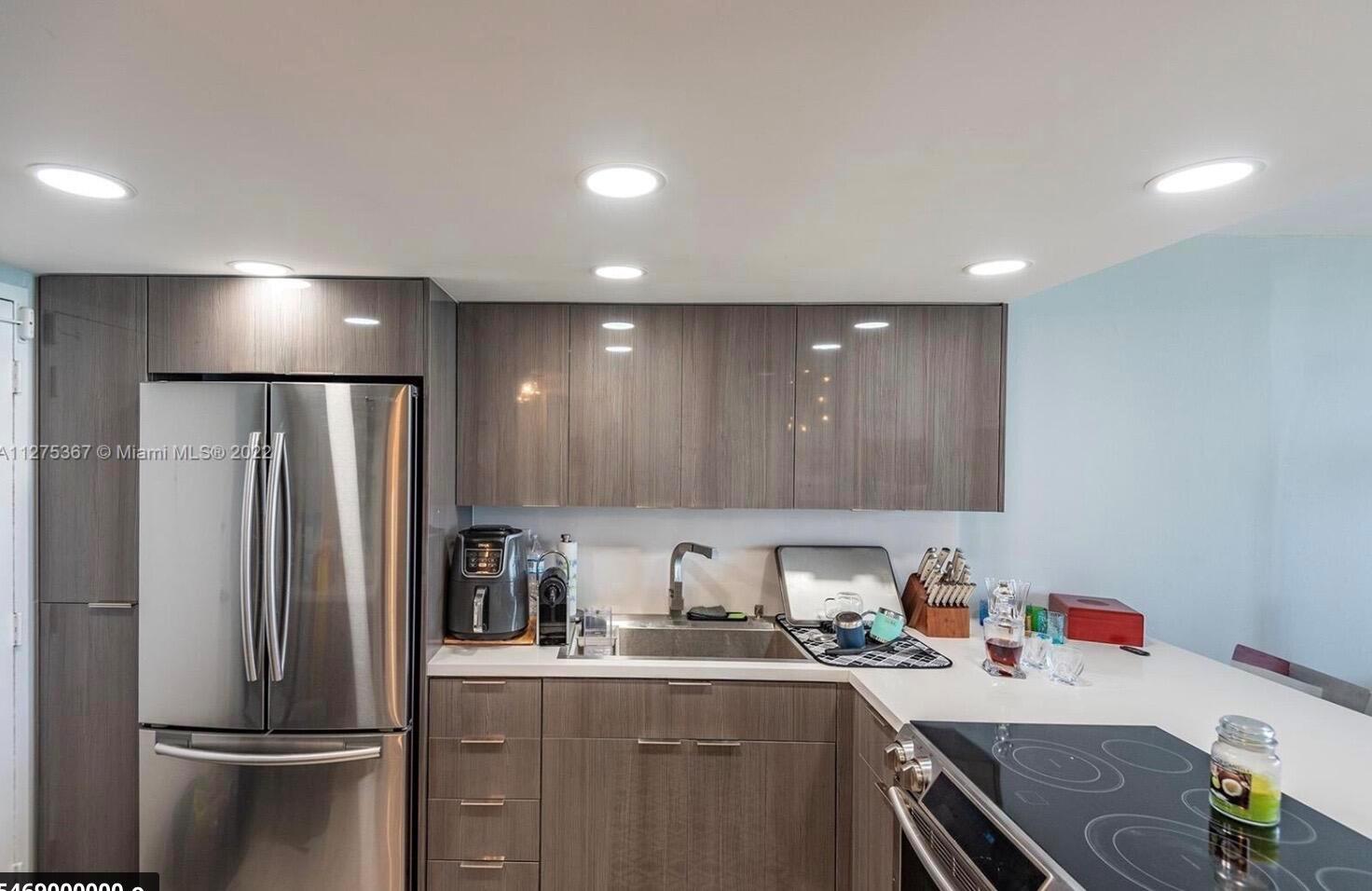 A modern kitchen features gray wood-grain cabinets, stainless steel appliances, and white countertops — 3180 S Ocean Drive # 414, Hallandale Beach FL 33009, HALLANDALE BEACH, FL