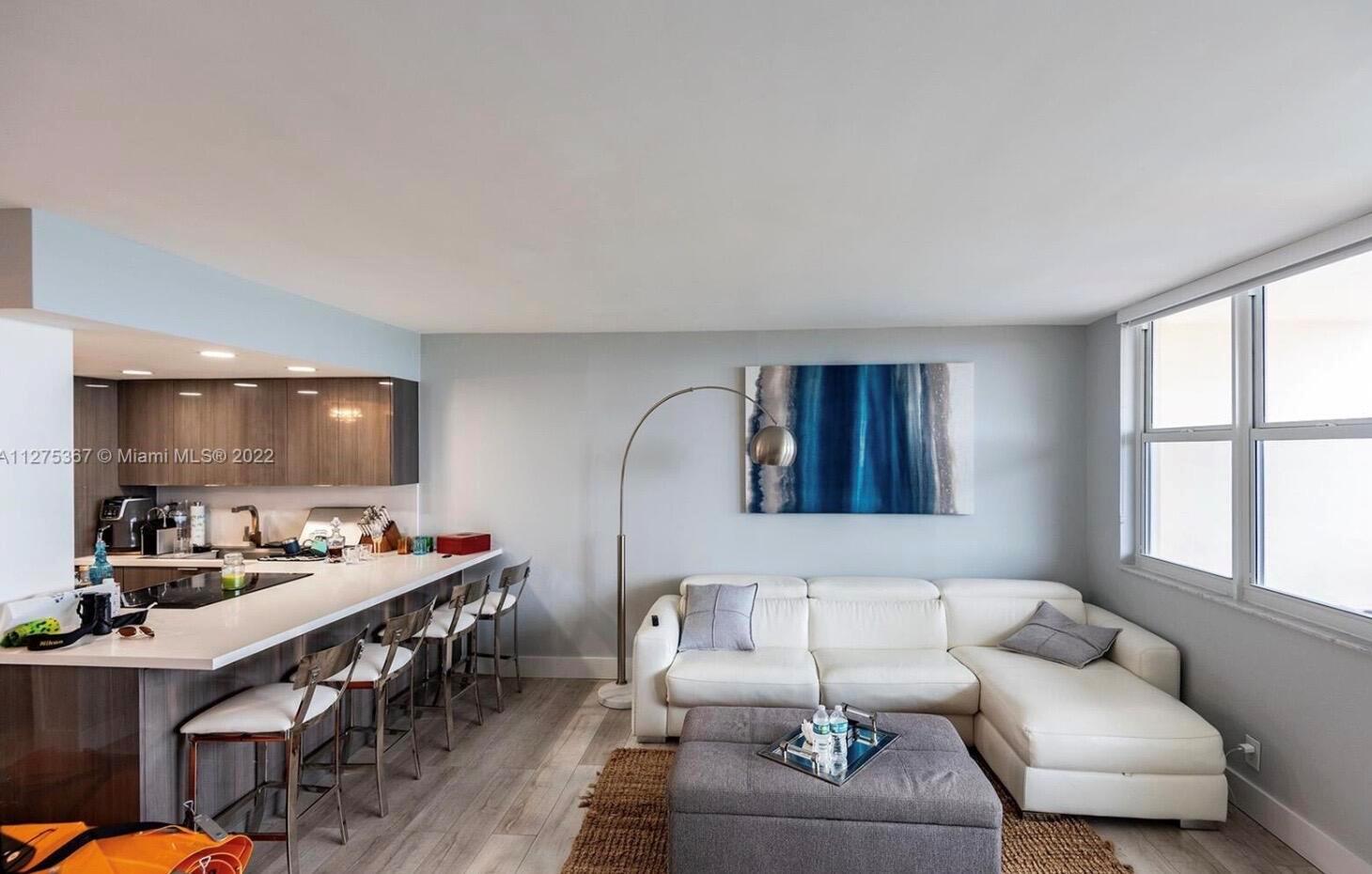 A modern living room features a white sectional sofa, a kitchen island, and bar stools — 3180 S Ocean Drive # 414, Hallandale Beach FL 33009, HALLANDALE BEACH, FL