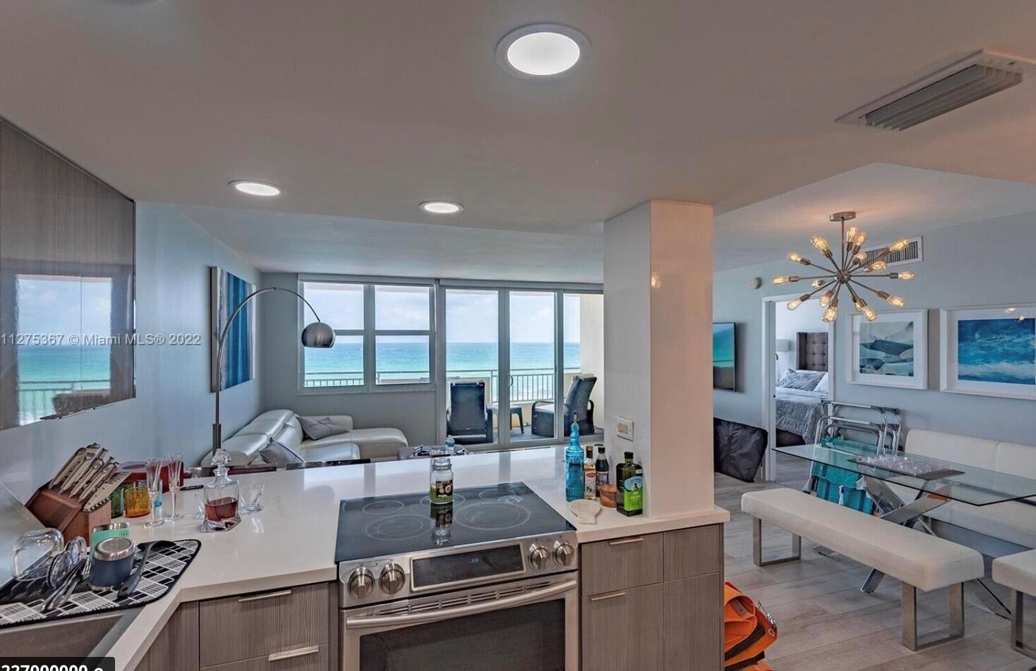 A kitchen with white countertops and stainless steel appliances overlooks a living area and ocean — 3180 S Ocean Drive # 414, Hallandale Beach FL 33009, HALLANDALE BEACH, FL