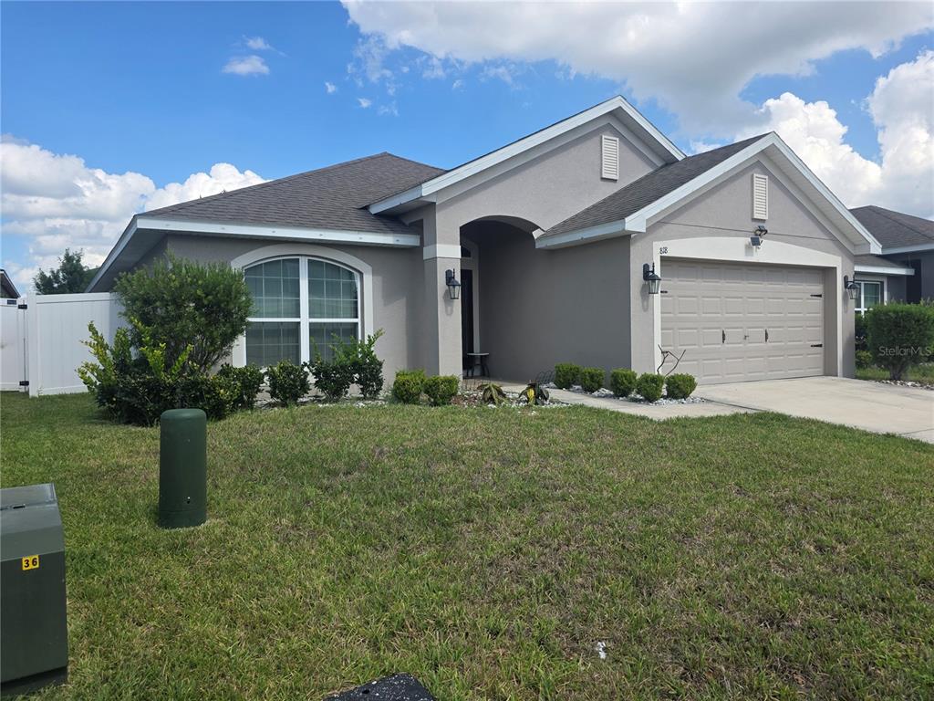 A single-story house with a gray stucco exterior, a two-car garage, and a front lawn — 818 LANDMARK HILLS DRIVE, HAINES CITY, FL