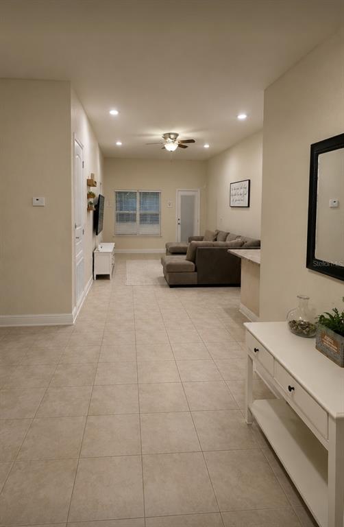A living room with tile floors, a gray sectional sofa, and a white console table — 818 LANDMARK HILLS DRIVE, HAINES CITY, FL