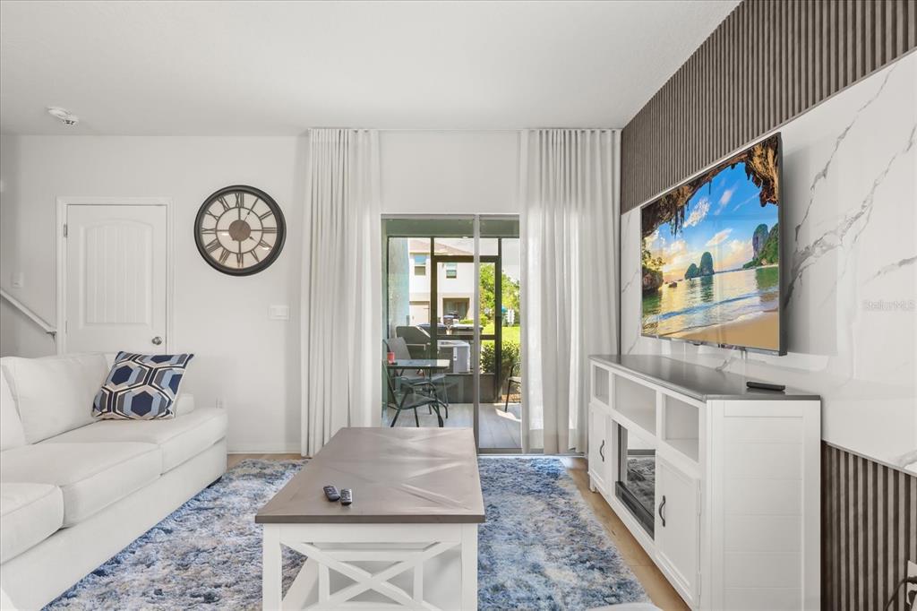 A living room features a white sofa, a coffee table, a television, and a patio — 10089 SALT POINT DRIVE, WINTER GARDEN, FL