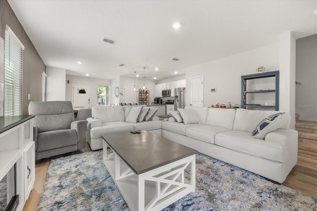 A living room features a white sectional sofa, a gray armchair, and a coffee table — 10089 SALT POINT DRIVE, WINTER GARDEN, FL