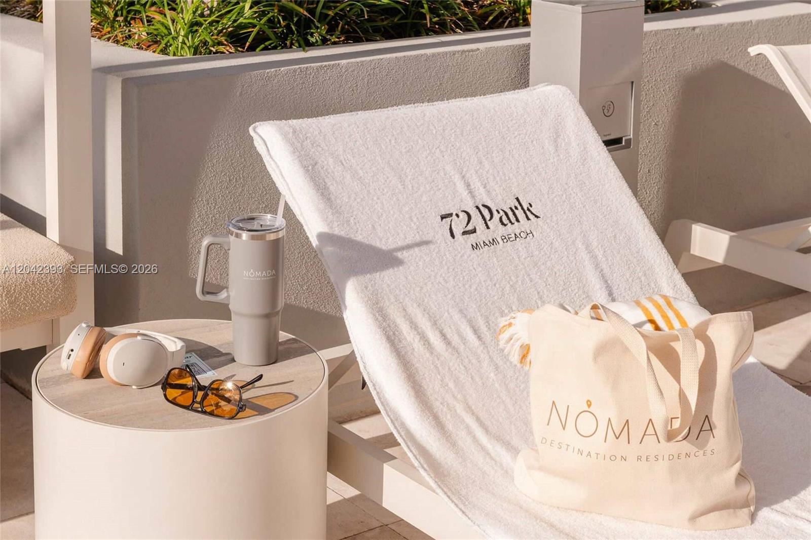 A lounge chair with a branded towel sits on a patio next to a table — 580 72nd St # 1811, Miami Beach FL 33141, MIAMI BEACH, FL