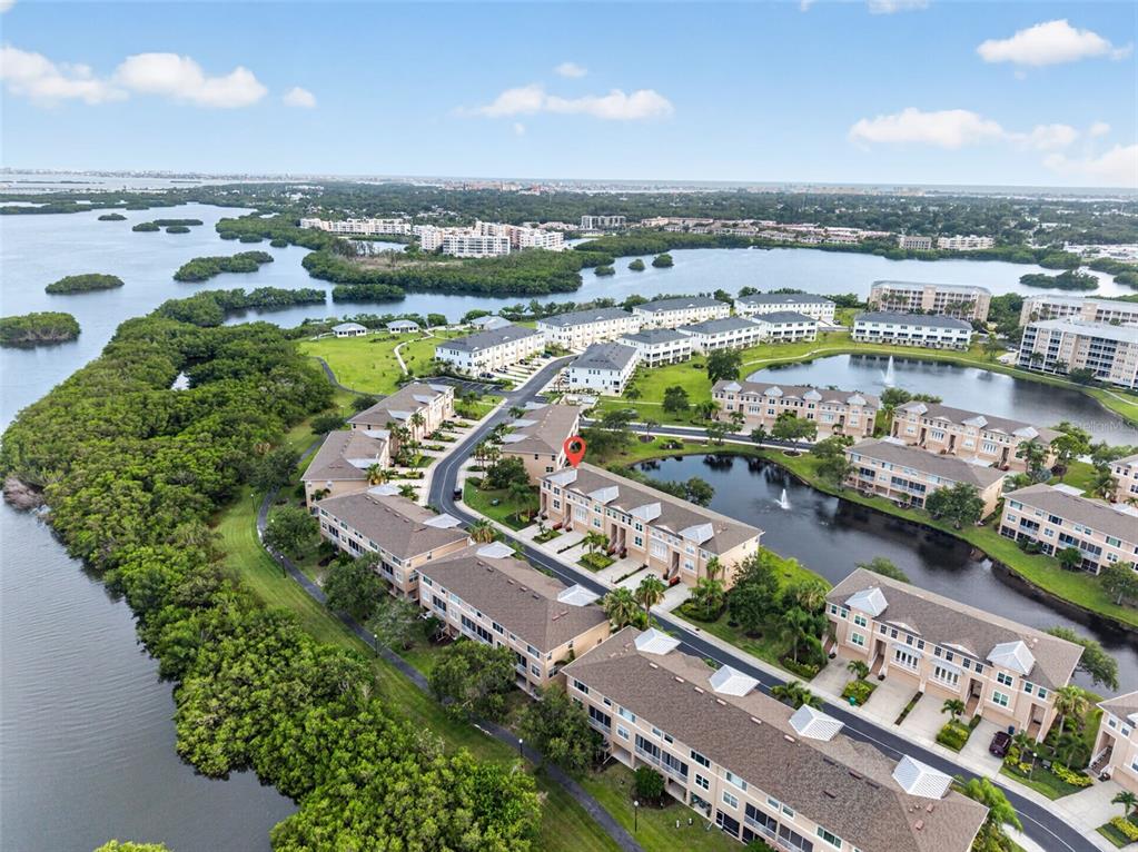 An aerial view shows a multi-story residential complex surrounded by water and mangroves — 7172 ISLAMORADA CIRCLE, SEMINOLE, FL