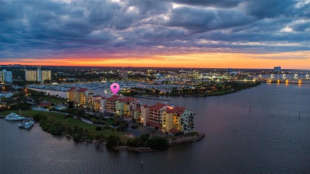 An aerial view of a waterfront apartment complex at sunset with a pink location pin — 661 MARINA POINT DRIVE UNIT 661, DAYTONA BEACH, FL