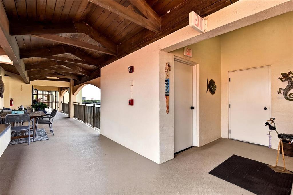 A covered outdoor balcony features a wooden beamed ceiling, dining furniture, and two white doors — 661 MARINA POINT DRIVE UNIT 661, DAYTONA BEACH, FL