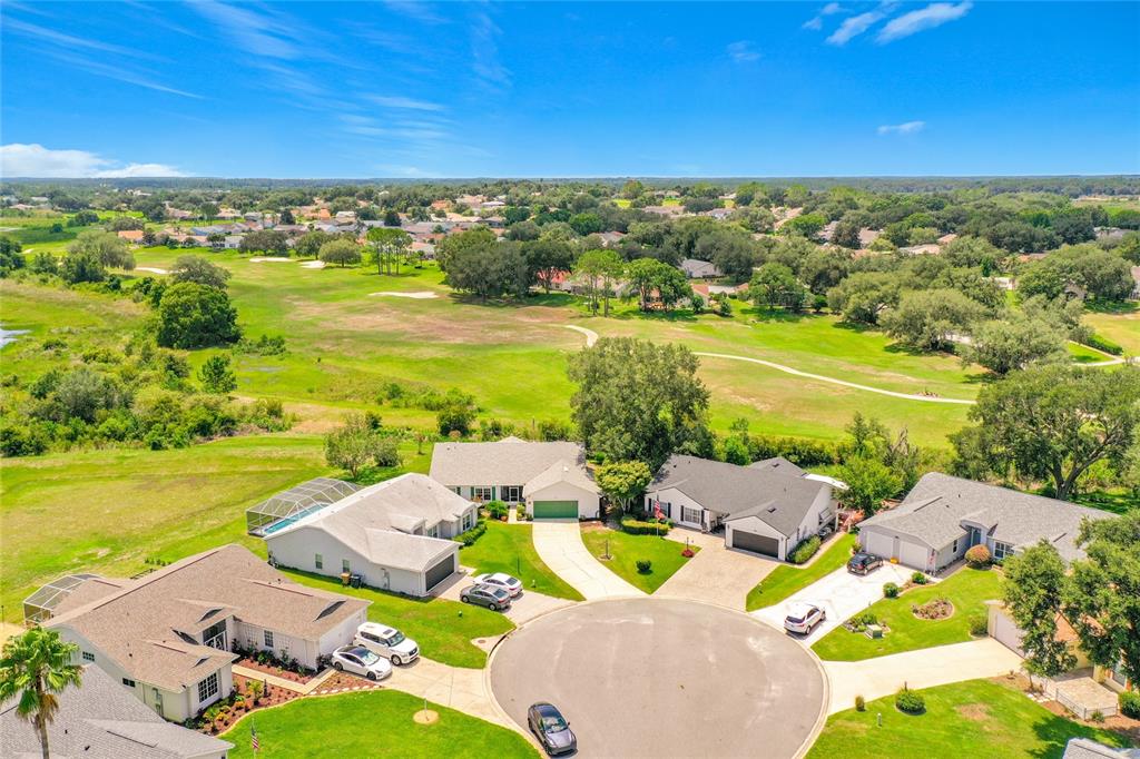 An aerial view shows suburban houses with driveways and pools bordering a large golf course — 25106 MERIWEATHER ROAD, LEESBURG, FL