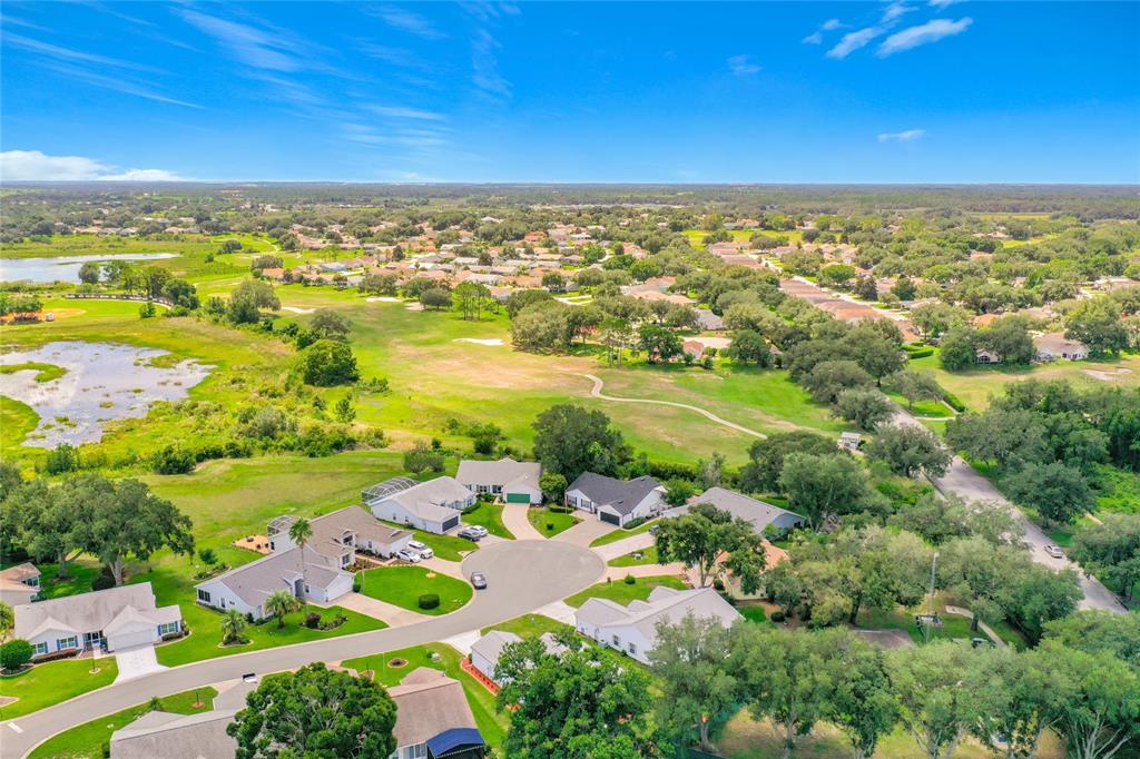 An aerial view of a suburban neighborhood with houses surrounding a cul-de-sac and green space — 25106 MERIWEATHER ROAD, LEESBURG, FL