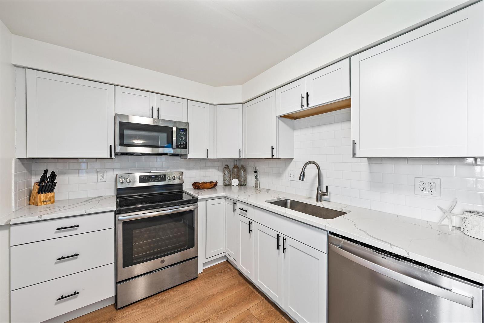 A kitchen with white cabinets, stainless steel appliances, and white marble-look countertops — 1605 S Us Highway 1 # 103, Jupiter FL 33477, JUPITER, FL