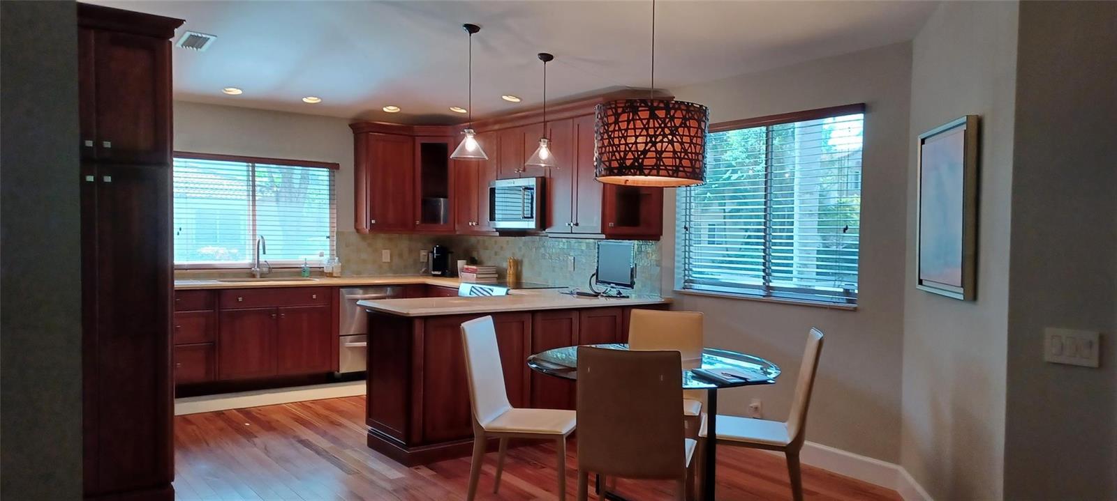 A kitchen with cherry wood cabinets, stainless steel appliances, and a glass-topped dining table — 6688 Via Regina, Boca Raton FL 33433, BOCA RATON, FL