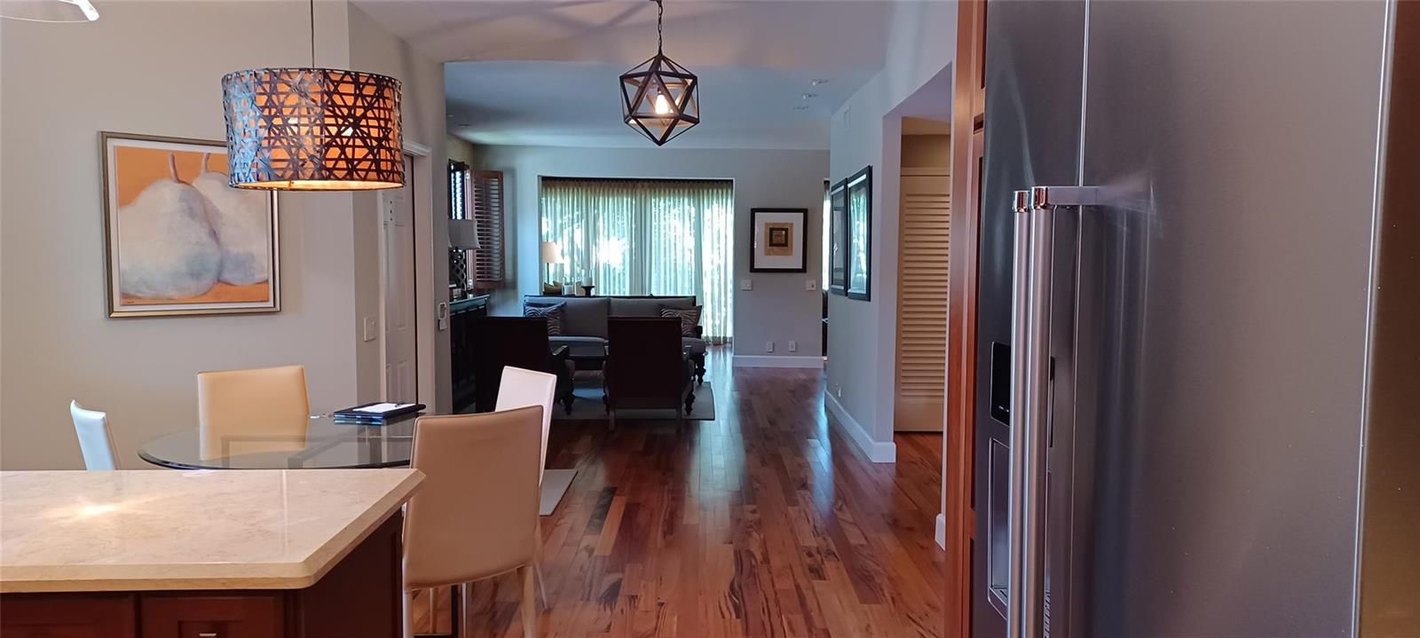 A dining area with a glass table leads into a living room with hardwood floors — 6688 Via Regina, Boca Raton FL 33433, BOCA RATON, FL