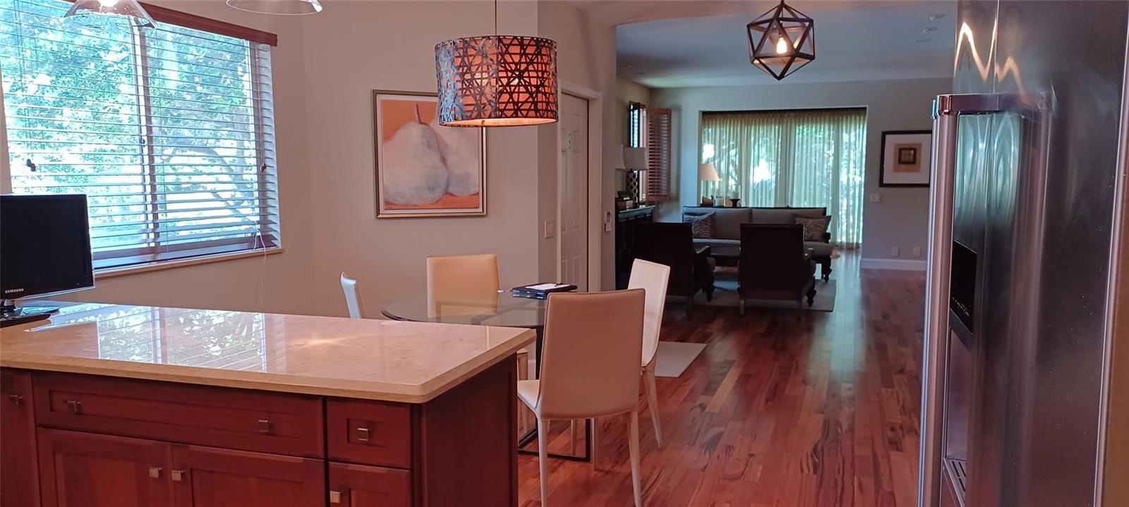 A kitchen island with a stone countertop overlooks a dining area and a living room — 6688 Via Regina, Boca Raton FL 33433, BOCA RATON, FL