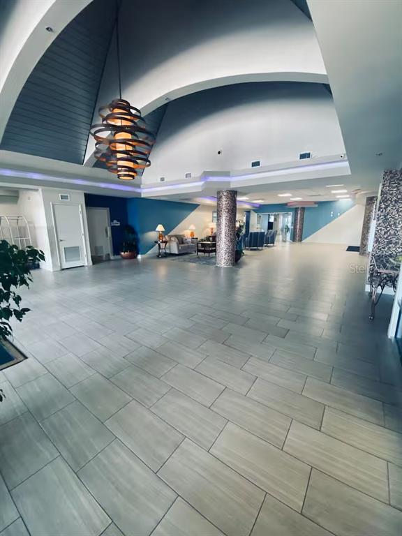 A spacious lobby features a vaulted ceiling, a modern chandelier, and light-colored tile flooring — 2700 N ATLANTIC AVENUE UNIT 1206, DAYTONA BEACH, FL