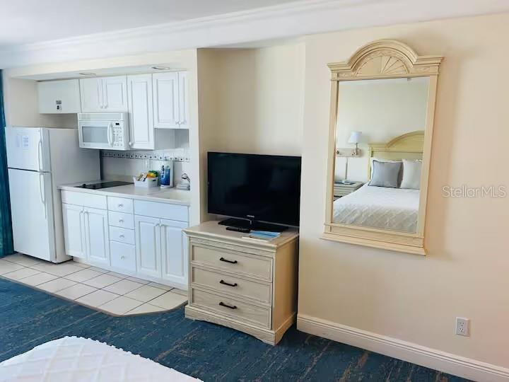 A hotel room features a kitchenette, a television on a dresser, and a wall mirror — 2700 N ATLANTIC AVENUE UNIT 1206, DAYTONA BEACH, FL