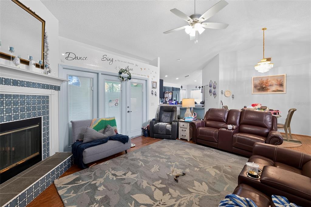 A living room features a tiled fireplace, brown leather furniture, and a ceiling fan — 4353 DINNER LAKE DRIVE, LAKE WALES, FL