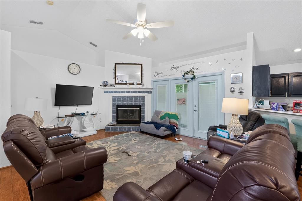 A living room features a fireplace, brown leather furniture, a ceiling fan, and sliding doors — 4353 DINNER LAKE DRIVE, LAKE WALES, FL
