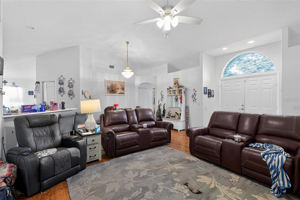 A living room features brown leather reclining sofas, a gray patterned rug, and vaulted ceilings — 4353 DINNER LAKE DRIVE, LAKE WALES, FL
