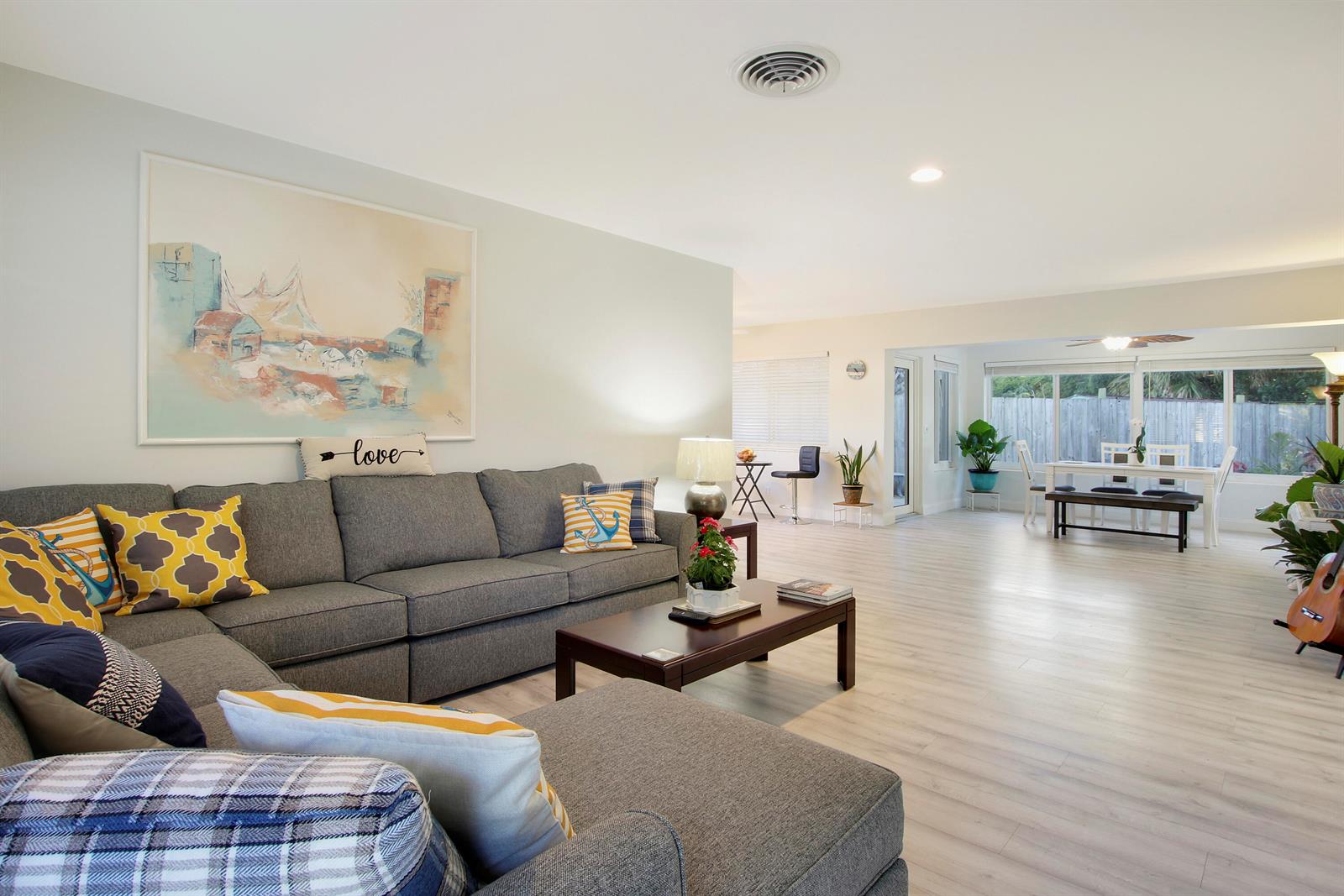 A living room with a gray sectional sofa, coffee table, and an open dining area — 466 Tequesta Drive, Tequesta FL 33469, TEQUESTA, FL