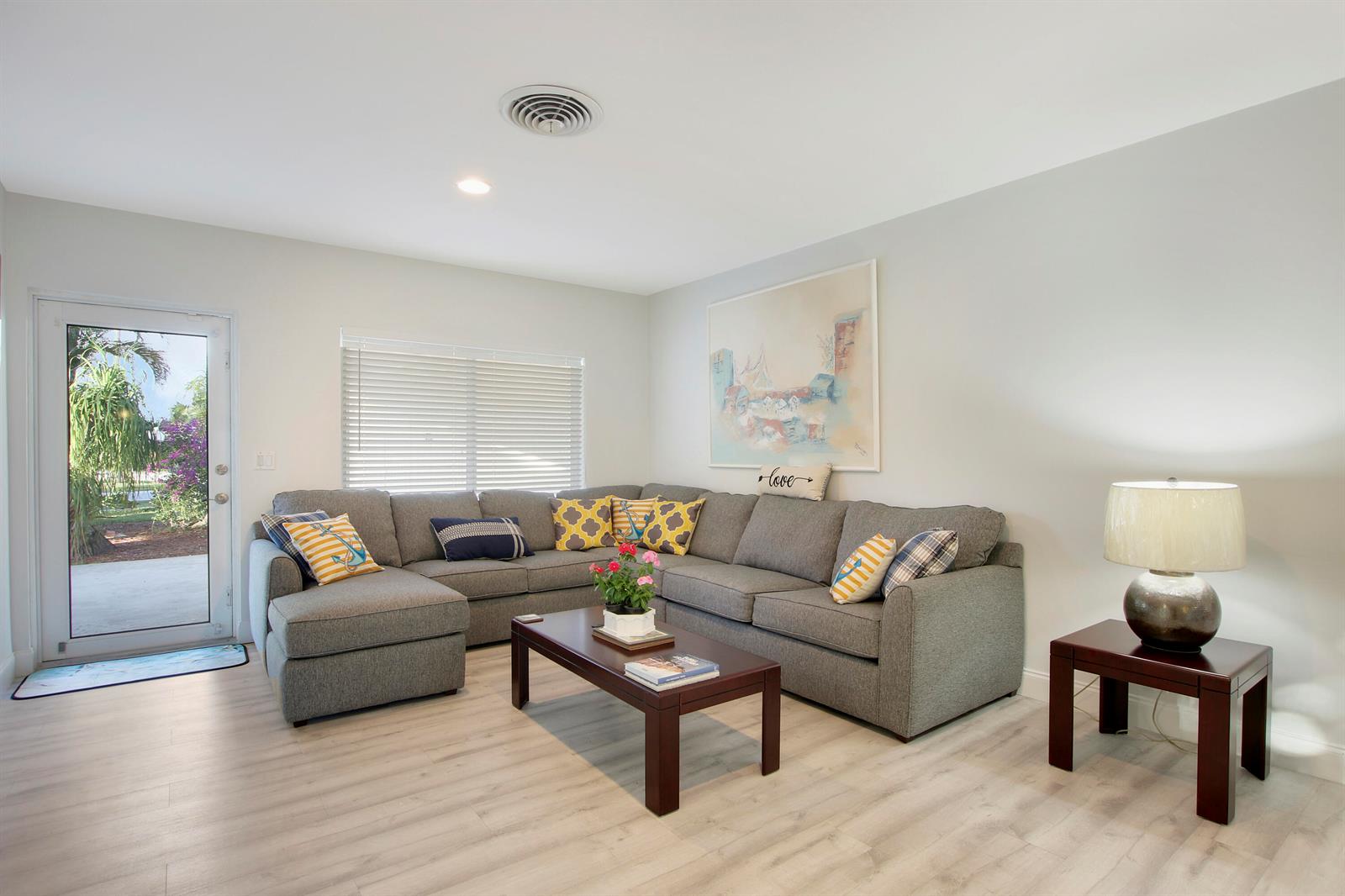 A living room features a grey sectional sofa, a dark wood coffee table, and light flooring — 466 Tequesta Drive, Tequesta FL 33469, TEQUESTA, FL