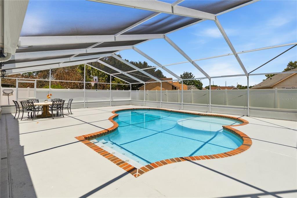 A screened-in patio features a swimming pool with a brick border and outdoor dining furniture — 8055 LESIA CIRCLE, ORLANDO, FL