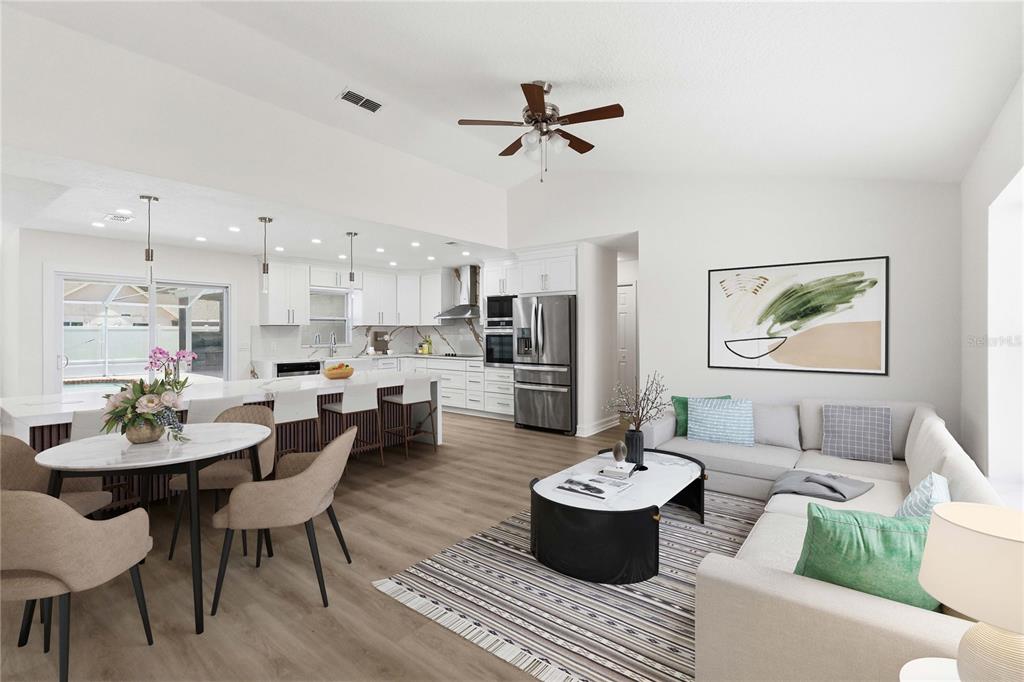 An open-concept kitchen and living area with white cabinetry, stainless appliances, and light wood flooring — 8055 LESIA CIRCLE, ORLANDO, FL