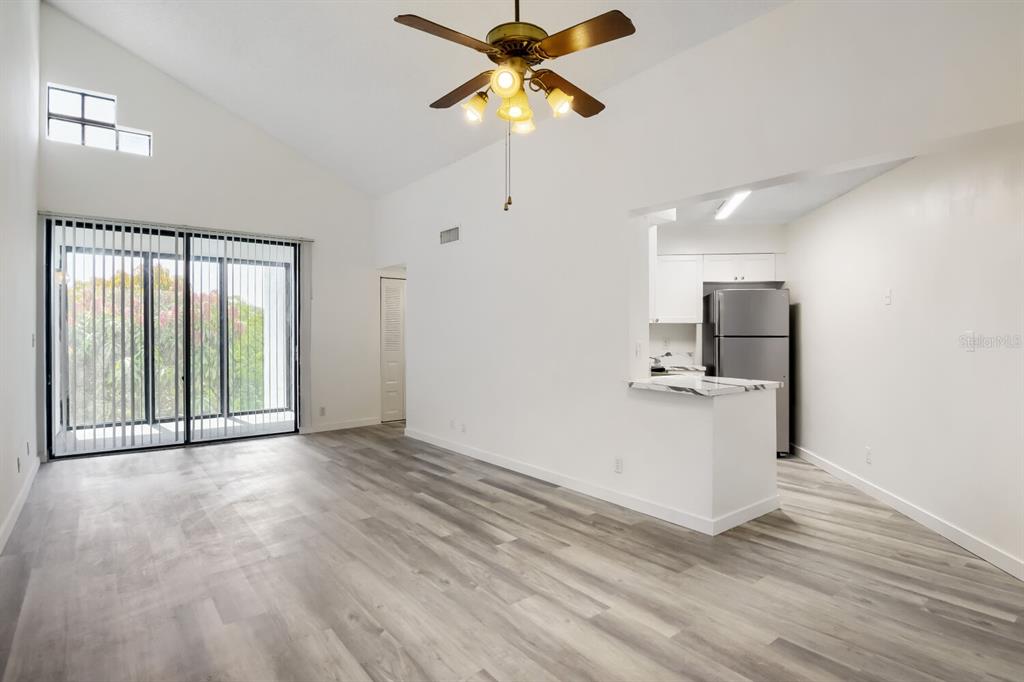 A living room with vaulted ceilings, wood-look flooring, and an open kitchen with stainless appliances — 210 LAKE POINTE CONDO FIVE DRIVE UNIT 304, OAKLAND PARK, FL