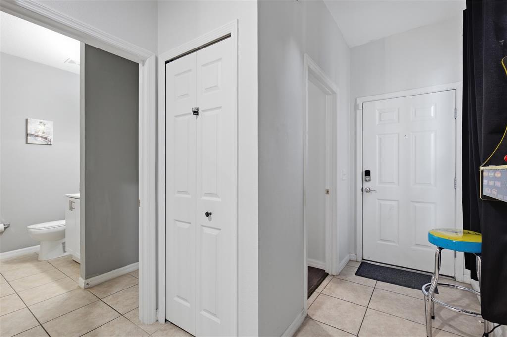 A tiled entryway features a white front door, a closet, and a doorway to a bathroom — 1717 RETREAT CIRCLE, CLERMONT, FL