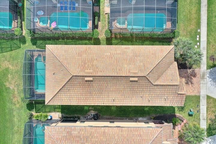 An aerial view shows a residential house with a tiled roof and screened-in swimming pools — 1627 LIMA AVE, KISSIMMEE, FL