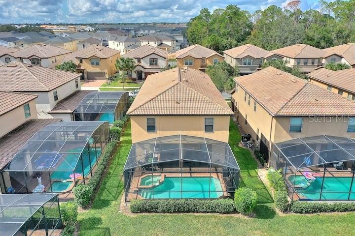 An aerial view shows several suburban houses with screened-in swimming pools in their backyards — 1627 LIMA AVE, KISSIMMEE, FL