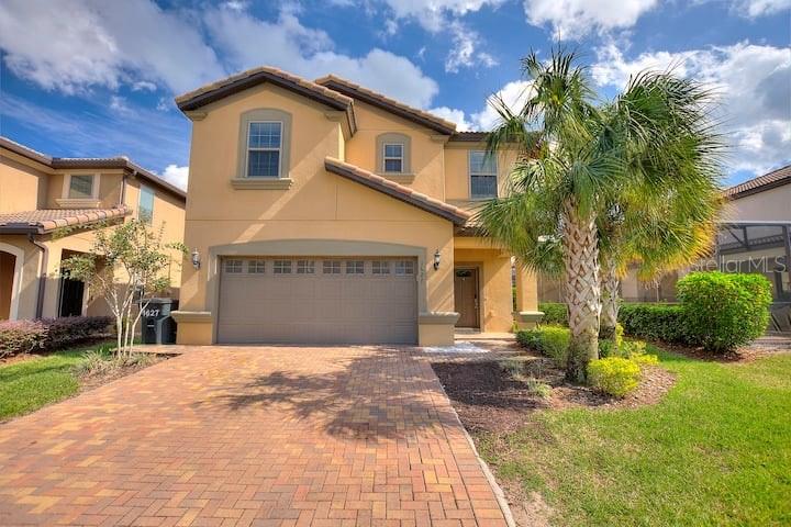 A two-story stucco house with a brick paver driveway and a palm tree in front — 1627 LIMA AVE, KISSIMMEE, FL
