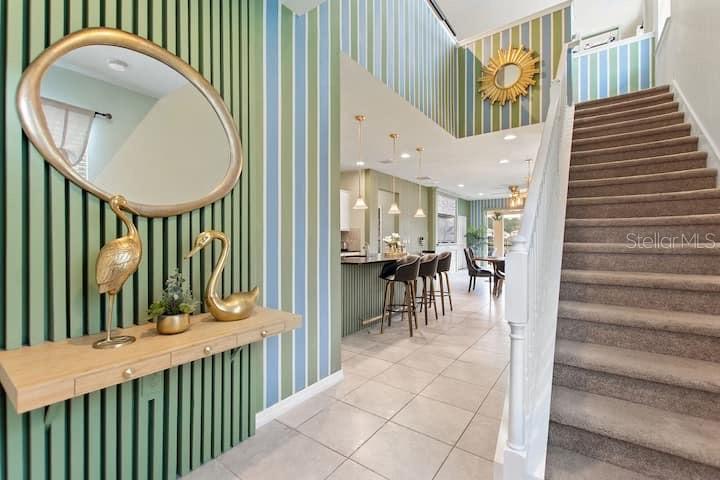 An entryway features a floating wooden console table, a gold-framed mirror, and a carpeted staircase — 1627 LIMA AVE, KISSIMMEE, FL