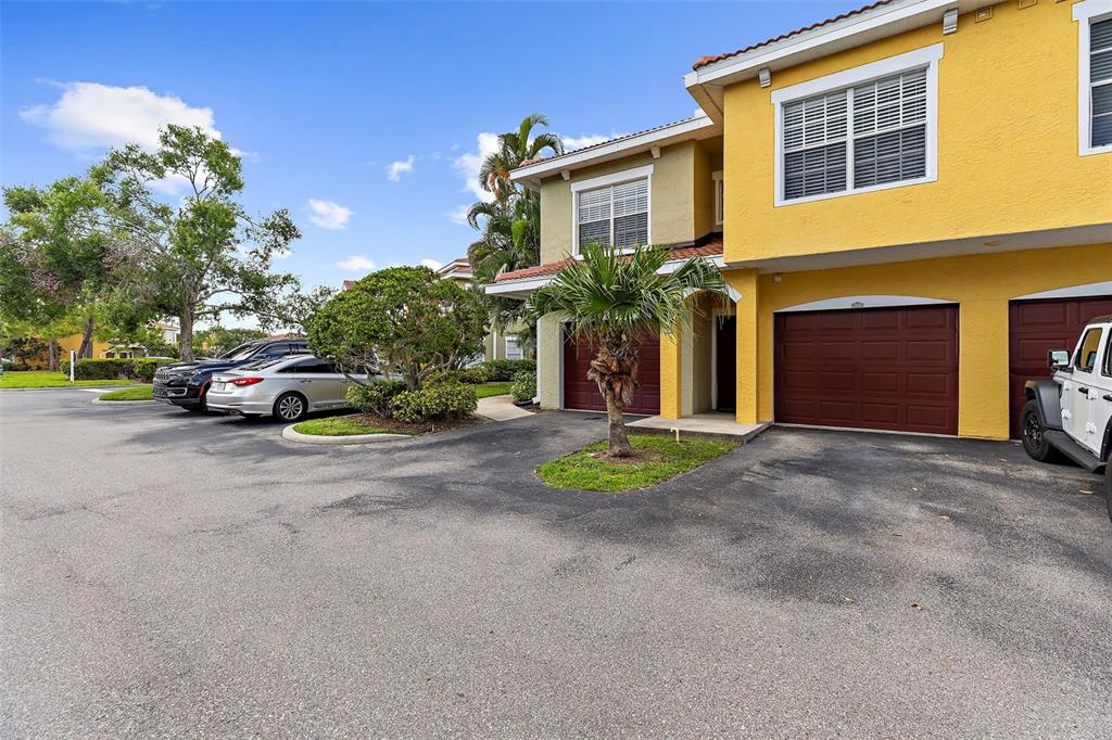 A yellow two-story townhouse with a brown garage door and a small palm tree — 5601 BENTGRASS DRIVE UNIT 102, SARASOTA, FL