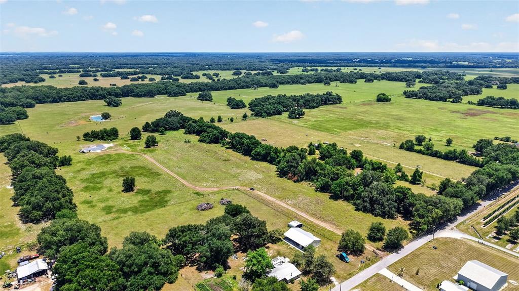 An aerial view shows a large rural property with open fields, scattered trees, and buildings — 7755 CR 714, CENTER HILL, FL