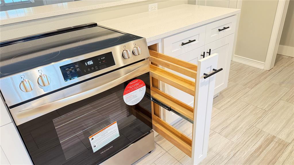 A stainless steel Frigidaire oven sits next to a pull-out wooden spice rack in a kitchen — 333 ISLAND WAY UNIT 101, CLEARWATER BEACH, FL