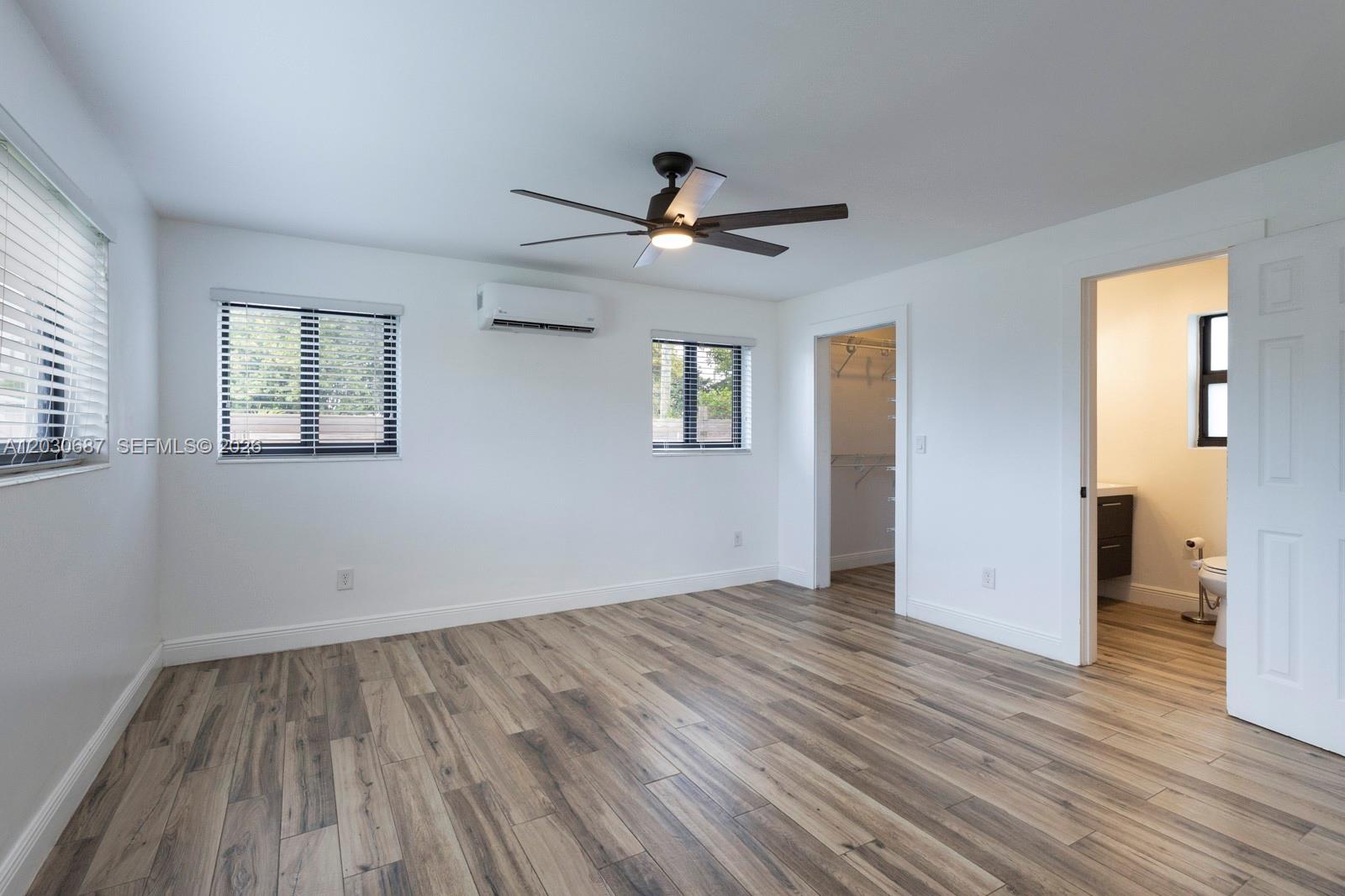 A bedroom with white walls, wood-look flooring, a ceiling fan, and an attached bathroom — 11431 SW 40th Ter, Miami FL 33165, MIAMI, FL
