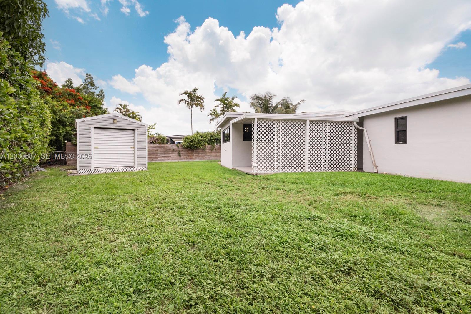 A backyard features a grassy lawn, a detached storage shed, and a lattice-enclosed patio area — 11431 SW 40th Ter, Miami FL 33165, MIAMI, FL
